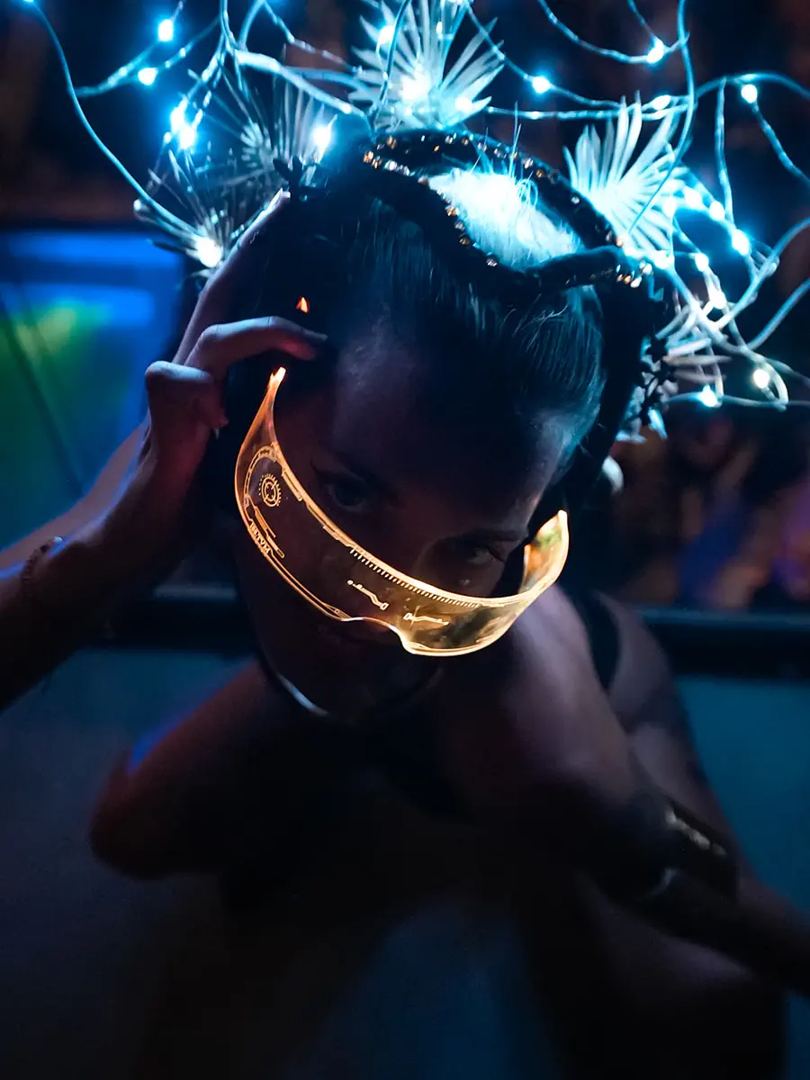 Retrato de una performer con máscara dorada y tocado de luces LED