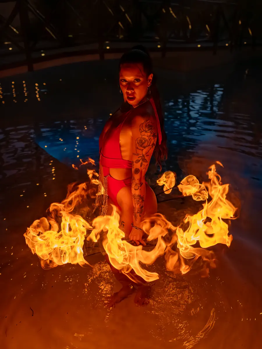 Performer de rojo dentro de la alberca rodeada por un aro de llamas