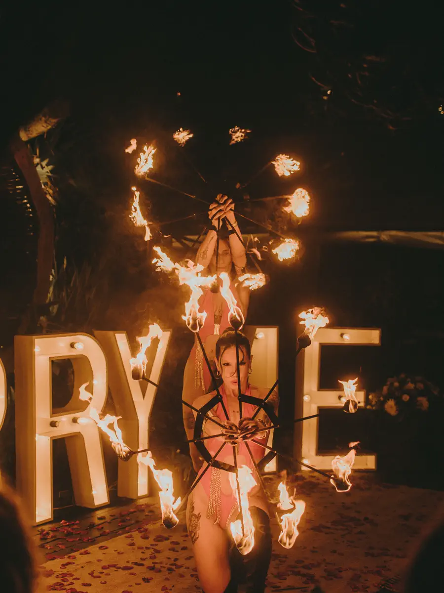 Performer de rodillas frente a letras gigantes encendidas en llamas